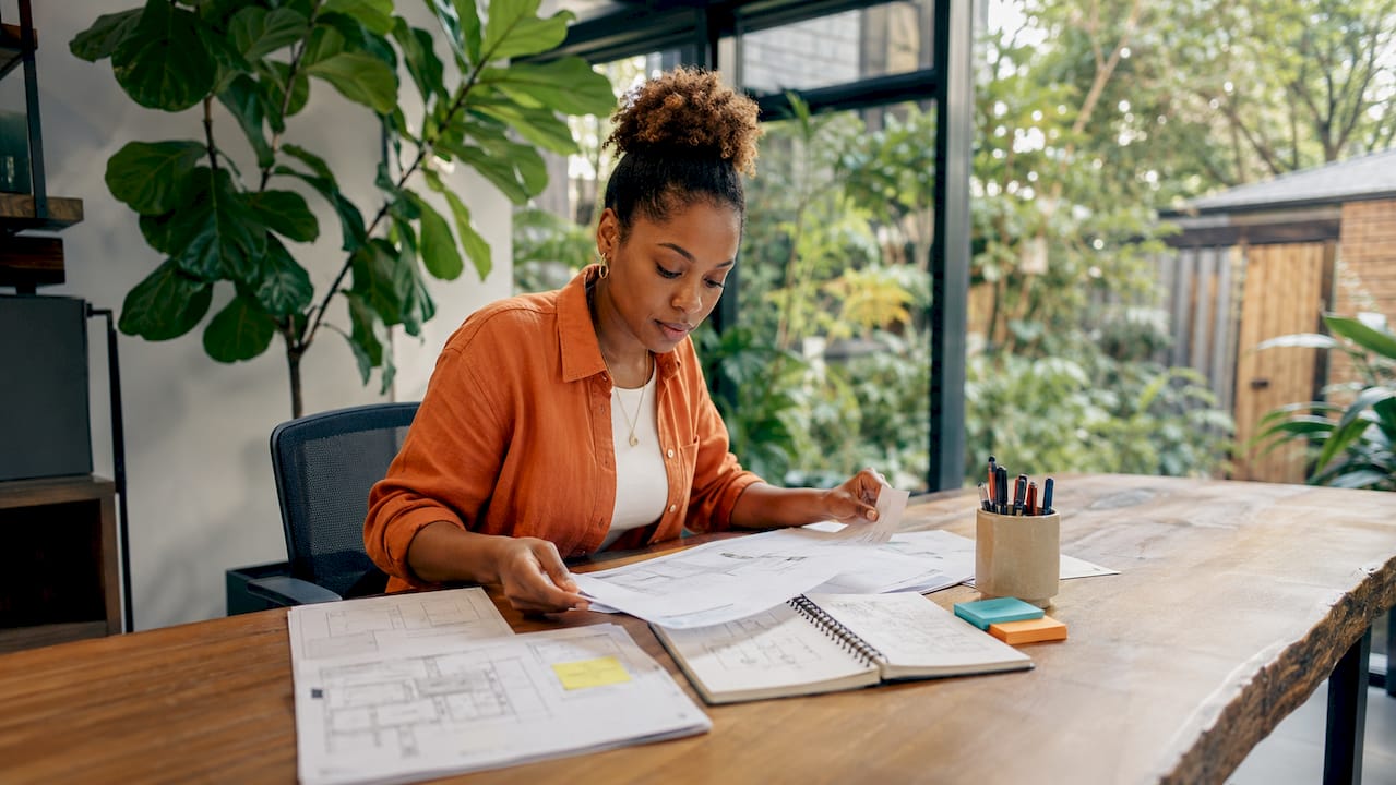 Woman arranging blueprints at bespoke office desk