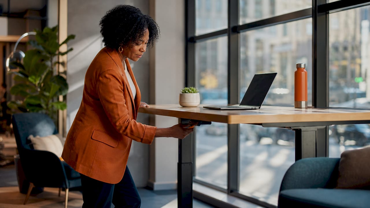 Woman adjusting height-adjustable desk in office