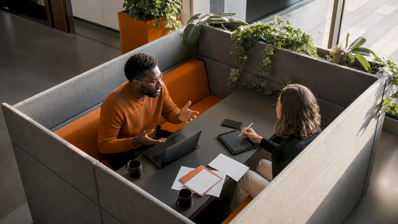 Office workers using modular desking pods in open-plan office