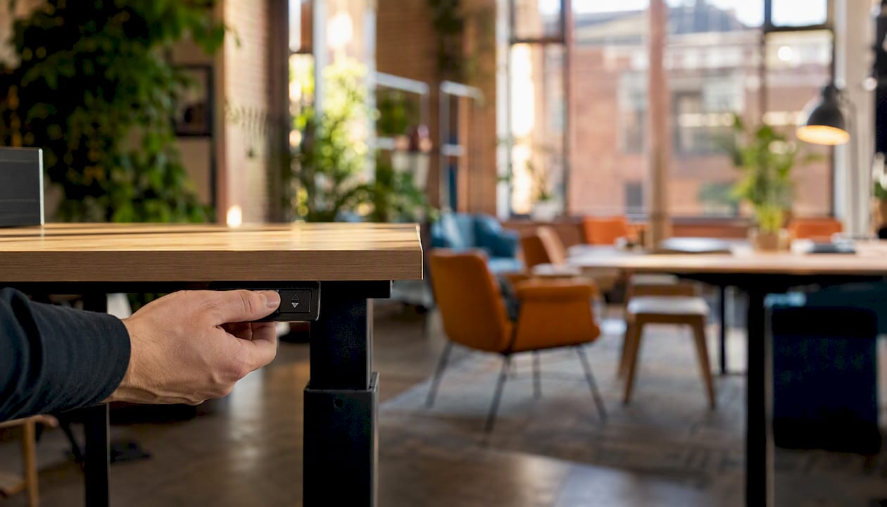 Hand adjusting height control on office desk