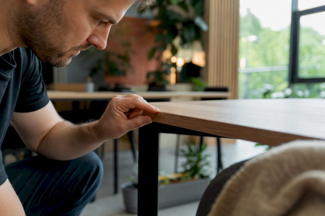 Hand inspecting office desk corner defect