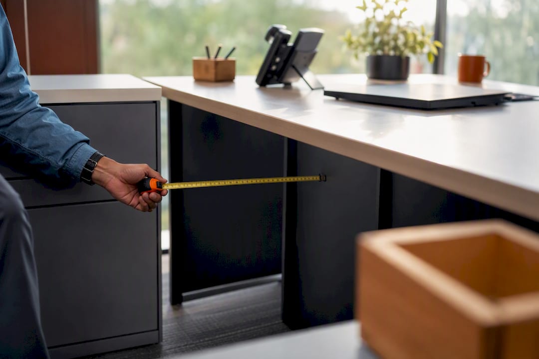 Hand measuring L-shaped desk corner clearance